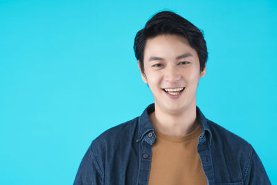 Portrait of smiling young man against blue background