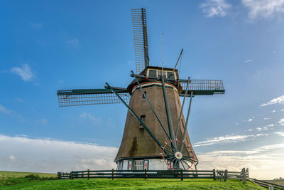 Traditional windmill on field against sky