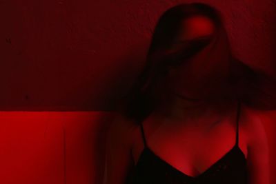 Close-up of woman with tousled hair standing by wall at night