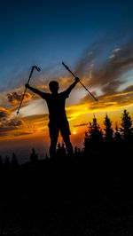 Silhouette man standing by tree against sky during sunset