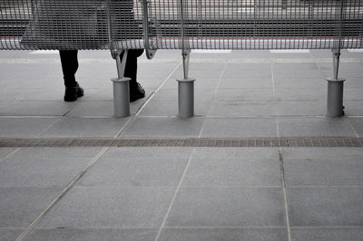 Low section of person sitting on bench at railroad station