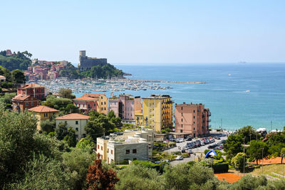 Buildings by sea against clear sky