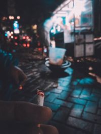 Rear view of man smoking cigarette on street at night