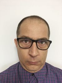 Portrait of young man wearing eyeglasses against white background