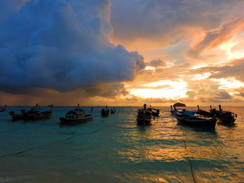 Boats moored in sea against sky during sunset