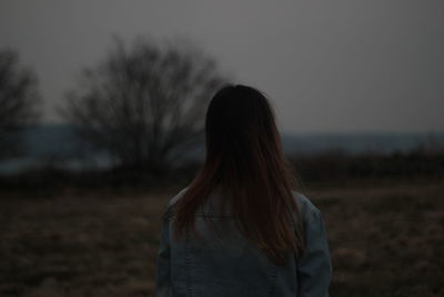 Rear view of woman standing on field against sky