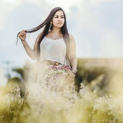 Portrait of young woman standing in field