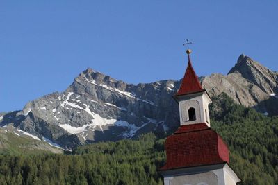 Low angle view of church and mountain against clear blue sky