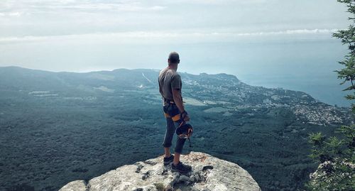 Rear view of man standing on rock against landscape