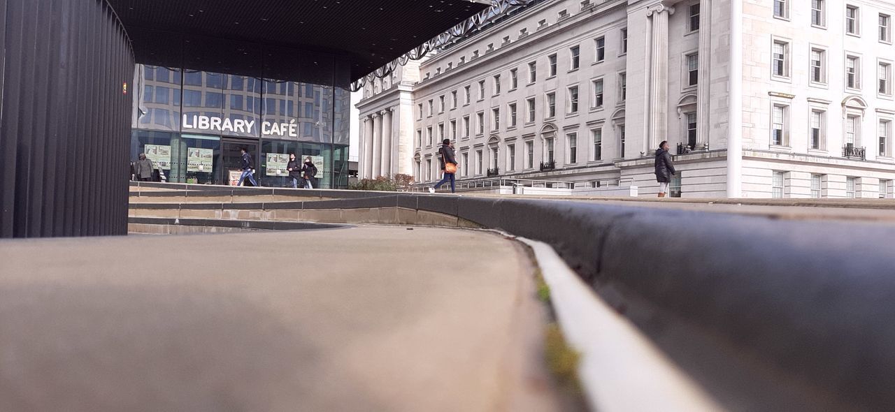 PEOPLE WALKING ON ROAD ALONG BUILDINGS