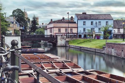 Boats moored at river against cloudy sky in city