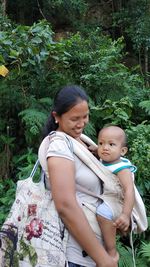 Mother carrying son while standing by plants