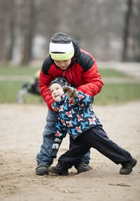 Full length of brothers standing at playground during winter