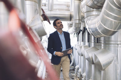 Smiling businessman looking at machinery in factory