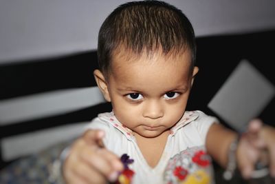 High angle portrait of baby girl sitting on bed at home