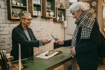 Senior male customer paying via tap to pay at checkout counter in home decor shop