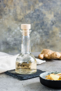 Ginger serum in a bottle and chopped ginger in a bowl on the table. alternative natural cosmetology. 