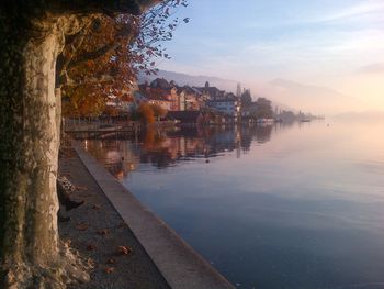 Buildings by lake against sky in city