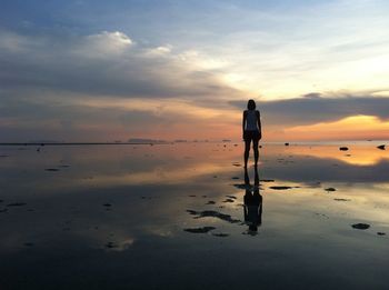 Man standing on beach against sky during sunset