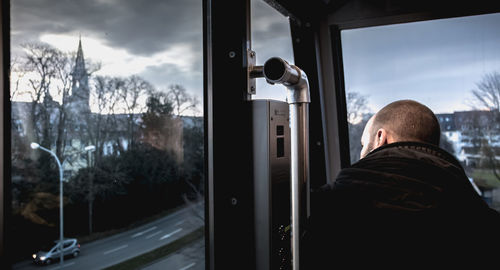 Rear view of man looking through train window