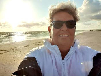 Portrait of man wearing sunglasses at beach against sky