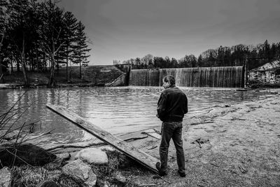 Rear view of man standing on riverbank