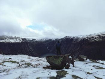 Man standing on rock against sky during winter