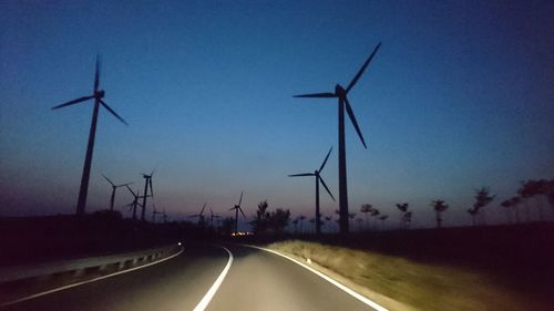 Wind turbines on road against sky