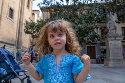 Portrait of young woman standing against building