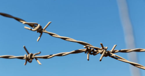 Low angle view of barbed wire against clear sky