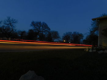 Light trails on road against clear sky at night