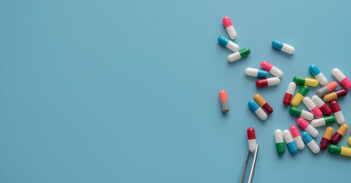 Directly above shot of pills spilling from bottle against green background