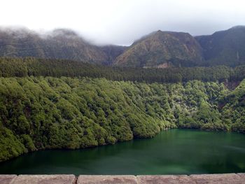 Scenic view of lake and mountains during foggy weather