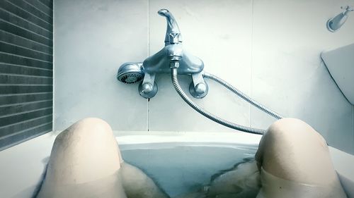 Midsection of person in bathtub at bathroom