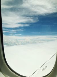 Close-up of airplane wing over landscape against sky