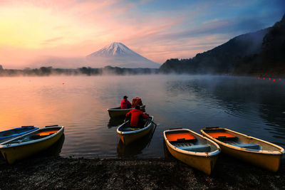 Boats in lake against sky during sunset