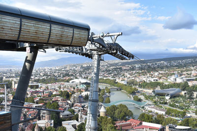 Overhead cable car over cityscape against sky