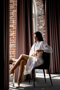 Portrait of young woman sitting on sofa at home