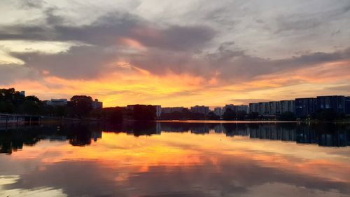 Reflection of buildings in lake against sky during sunset