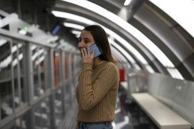 Young woman using mobile phone while standing in bus