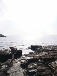 Rear view of man standing on beach against clear sky