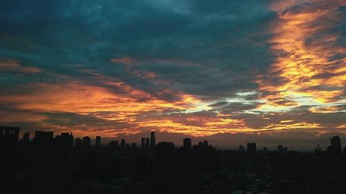 View of cityscape against cloudy sky during sunset