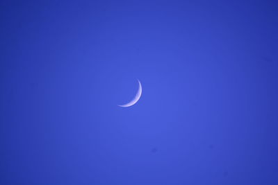 Low angle view of moon against blue sky at night