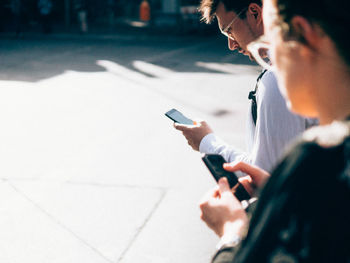 Side view of woman and man using smartphones on street