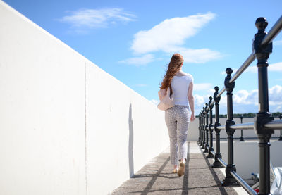 Woman standing by railing against sky