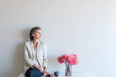 Full length of woman with flowers against white background