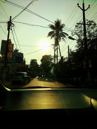 Cars on road in city against sky during sunset