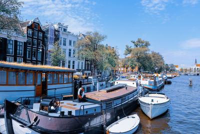 Boats moored in canal amidst buildings in city