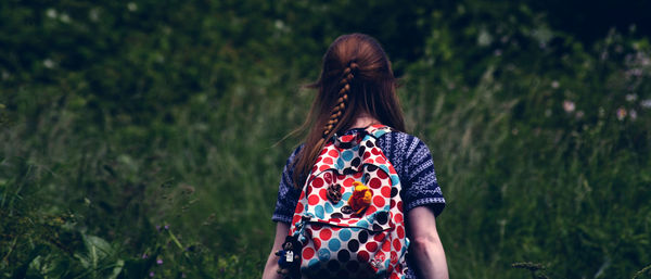 Rear view of woman with bag standing against plants