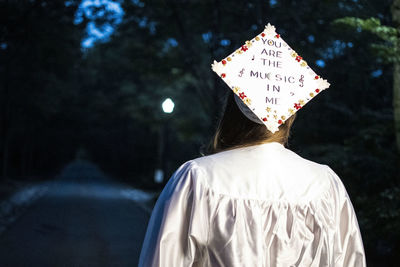 Rear view of woman standing against tree